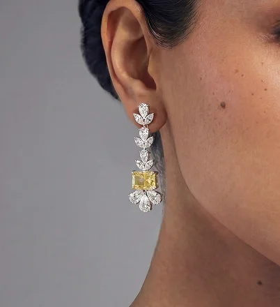 Close-up of woman wearing diamond drop earrings with yellow gemstone