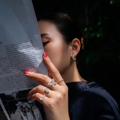 Woman holding magazine while wearing luxury diamond rings and hoop earrings