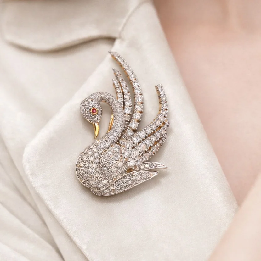 Swan-shaped diamond brooch pinned on ivory blazer lapel
